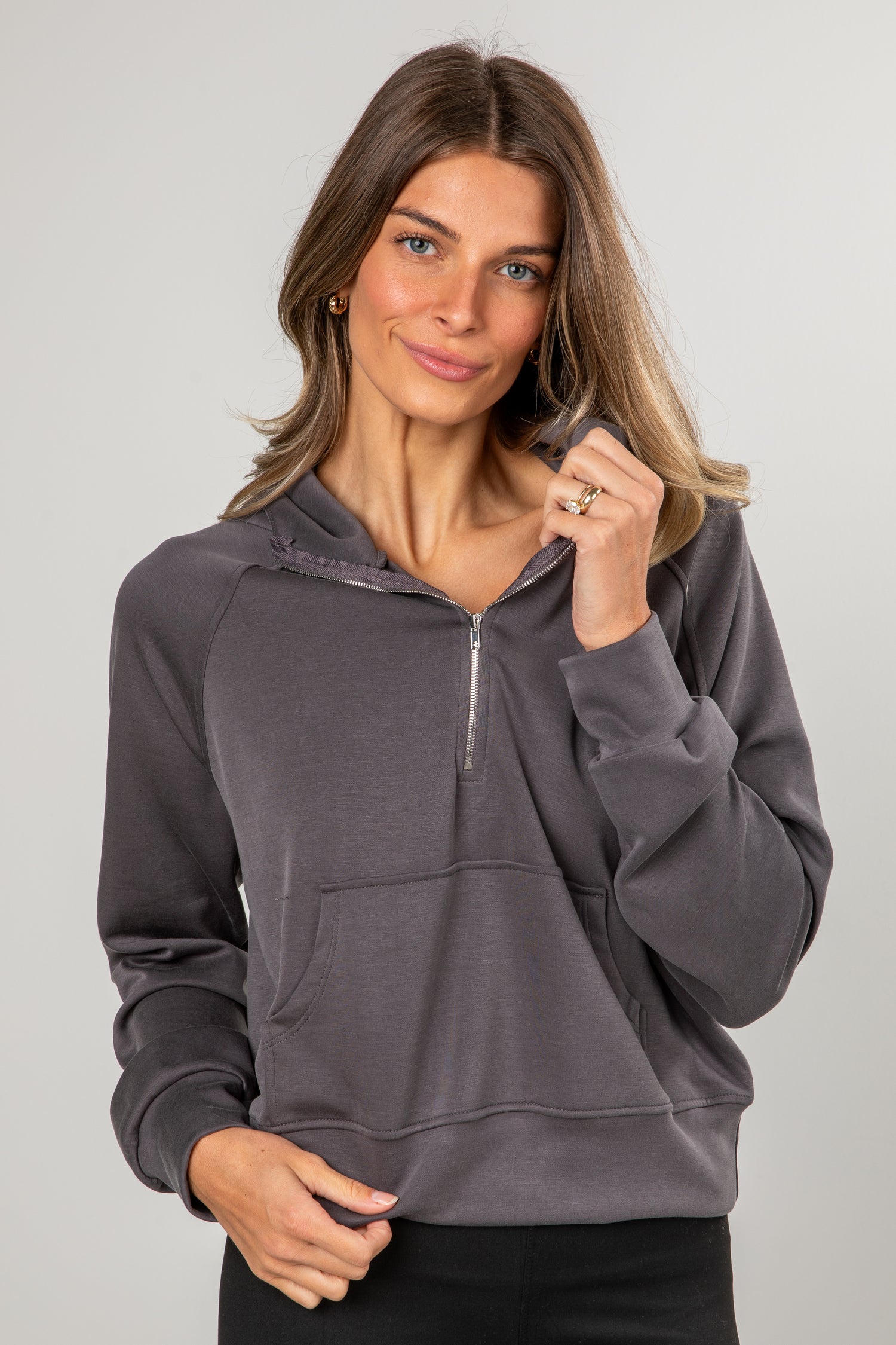Woman wearing a gray hoodie against a plain background