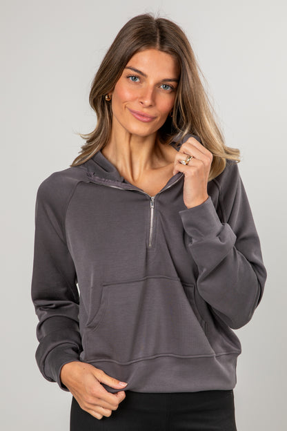 Woman wearing a gray hoodie against a plain background