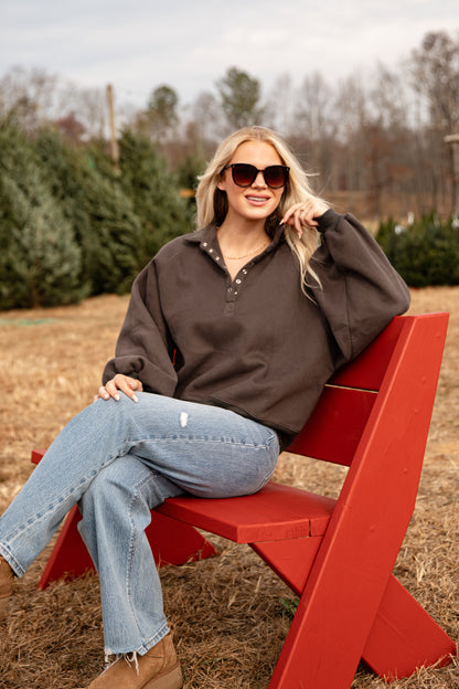 Woman sitting on a red bench in an outdoor setting with trees in the background