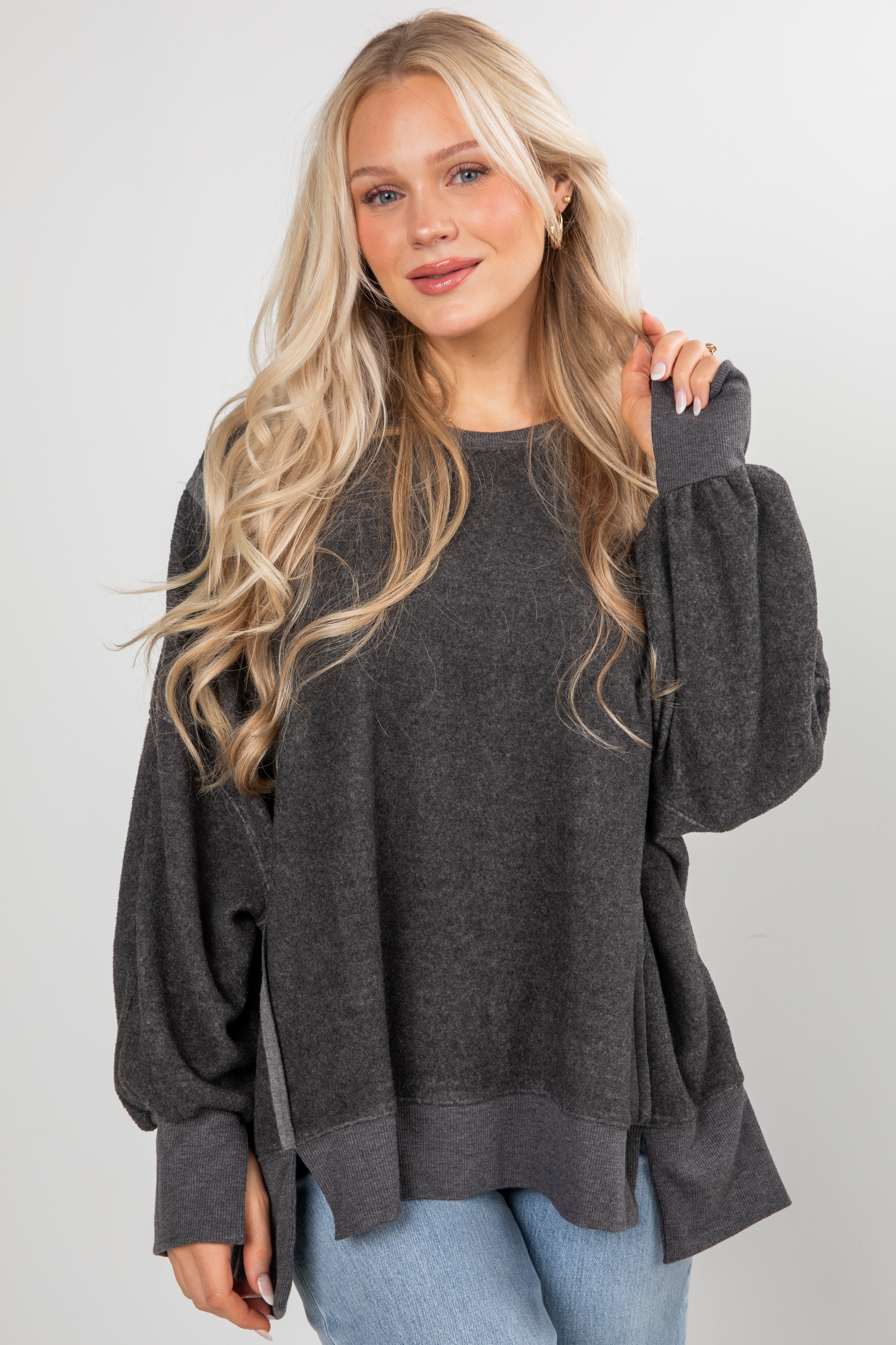 Woman wearing a dark gray oversized sweater against a plain background