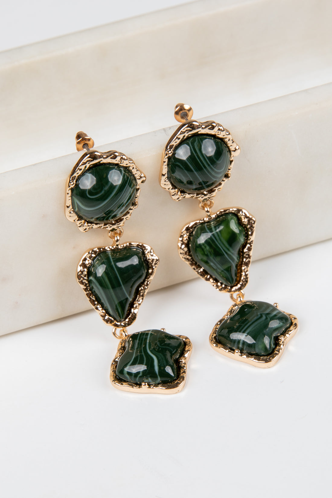Green gemstone earrings with gold accents on a white background