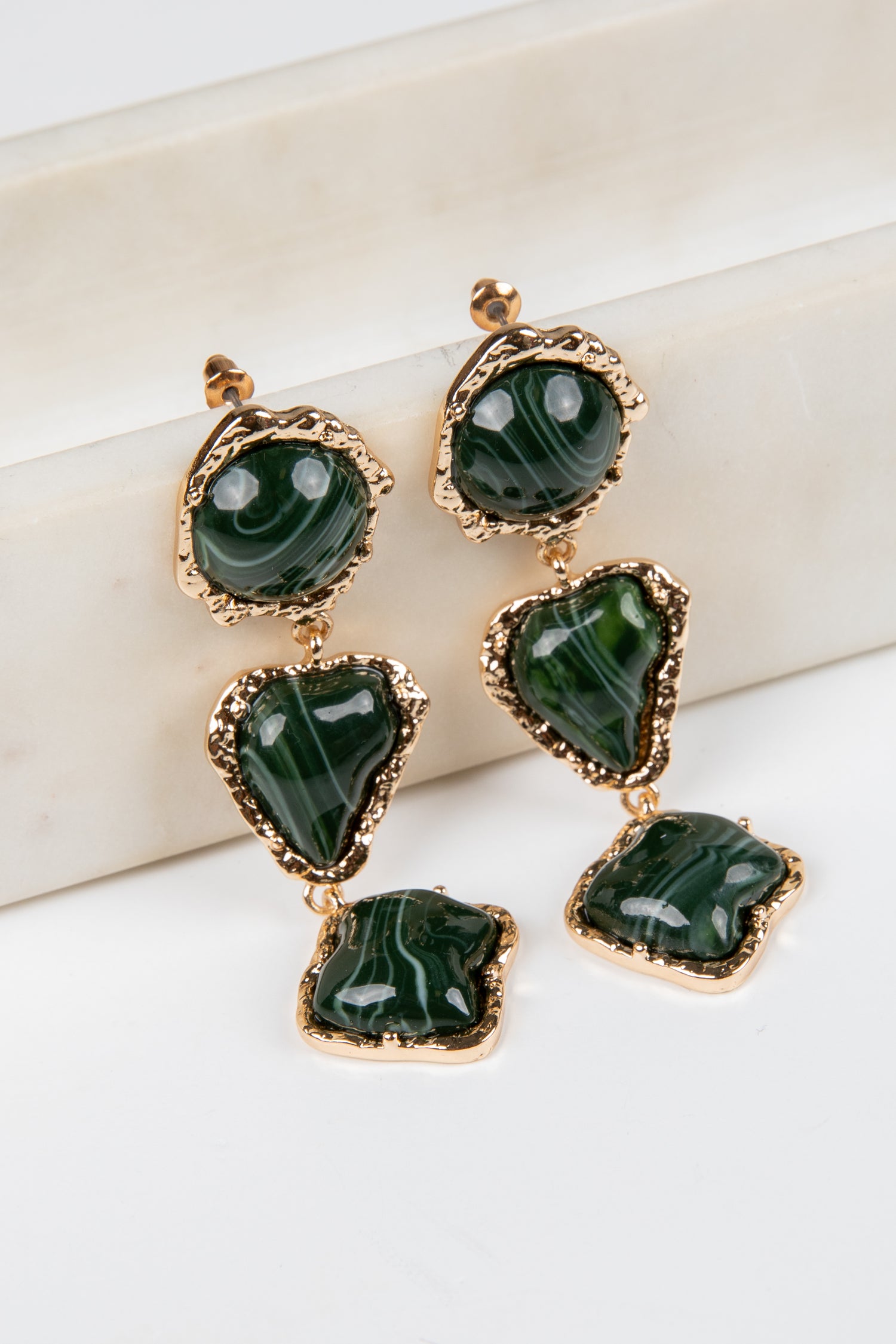 Green gemstone earrings with gold accents on a white background