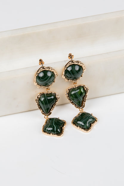 Green earrings with gold accents on a white surface