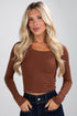 Woman wearing a brown long-sleeve top against a plain background