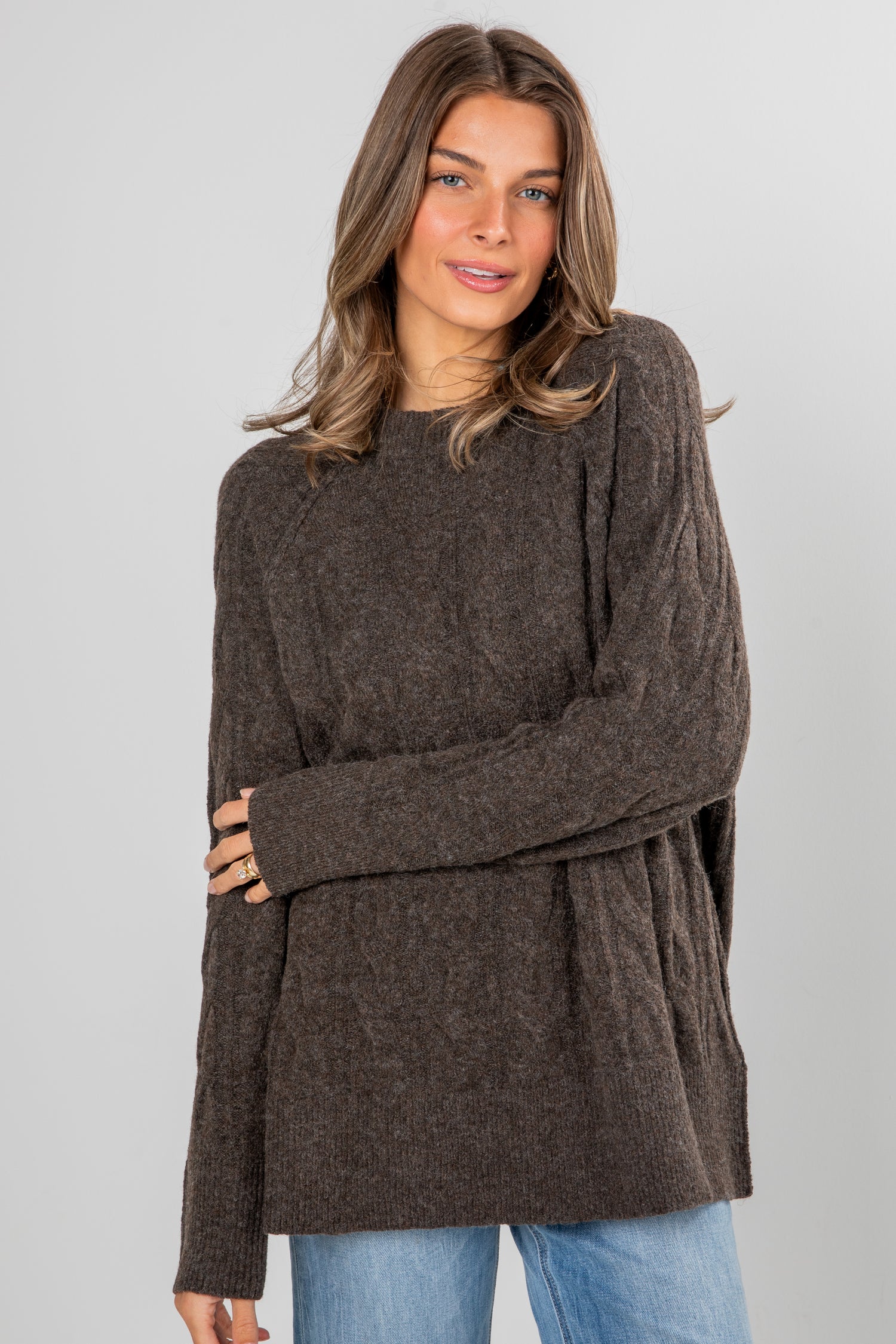 Woman wearing a brown sweater with a plain background