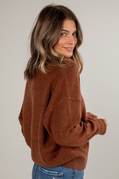Woman wearing a brown sweater against a plain background