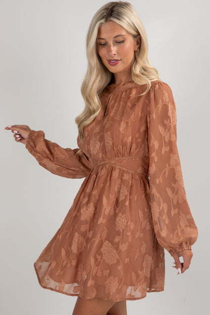 Woman wearing a brown floral dress against a plain background