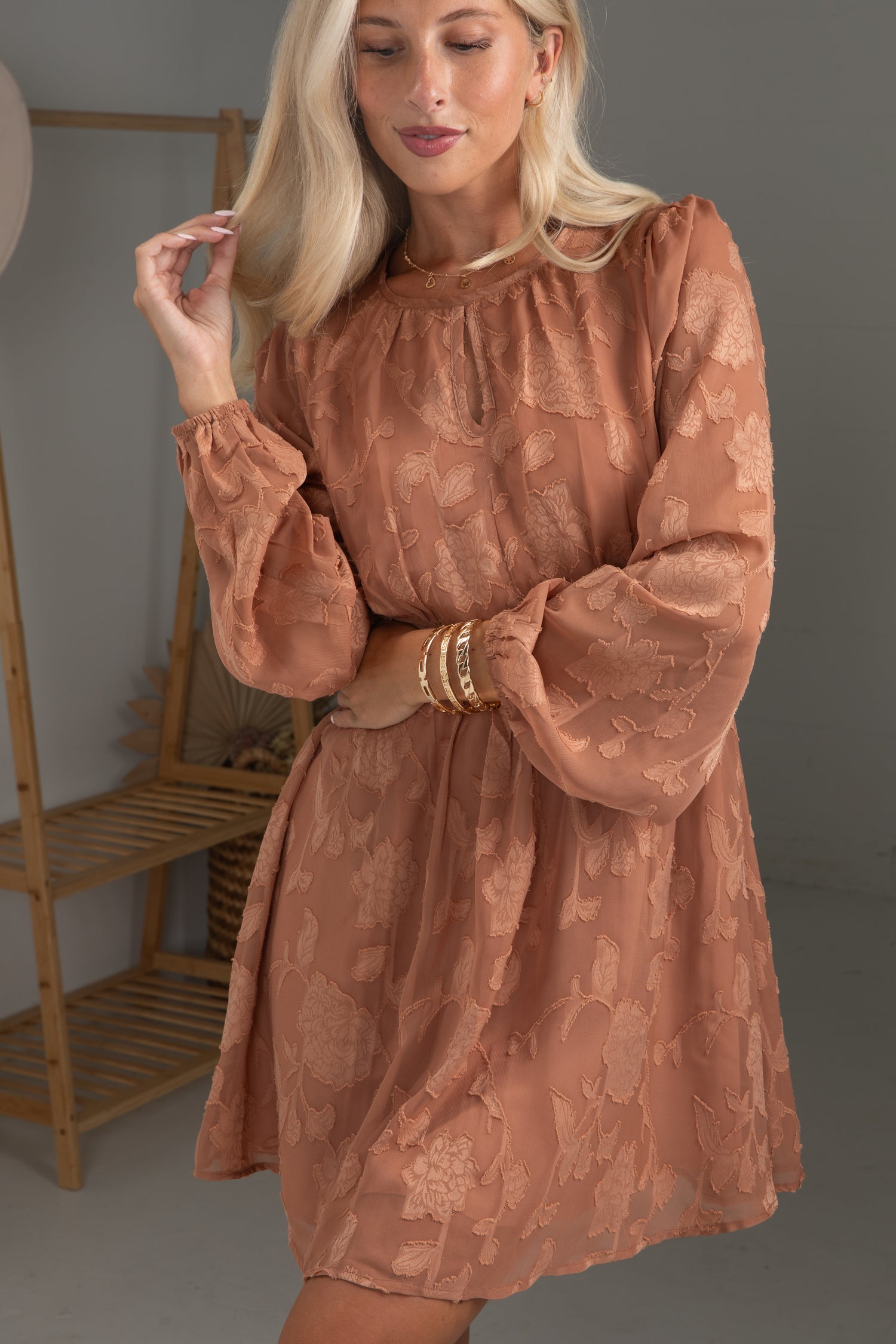 Woman wearing a brown floral dress in a minimal indoor setting