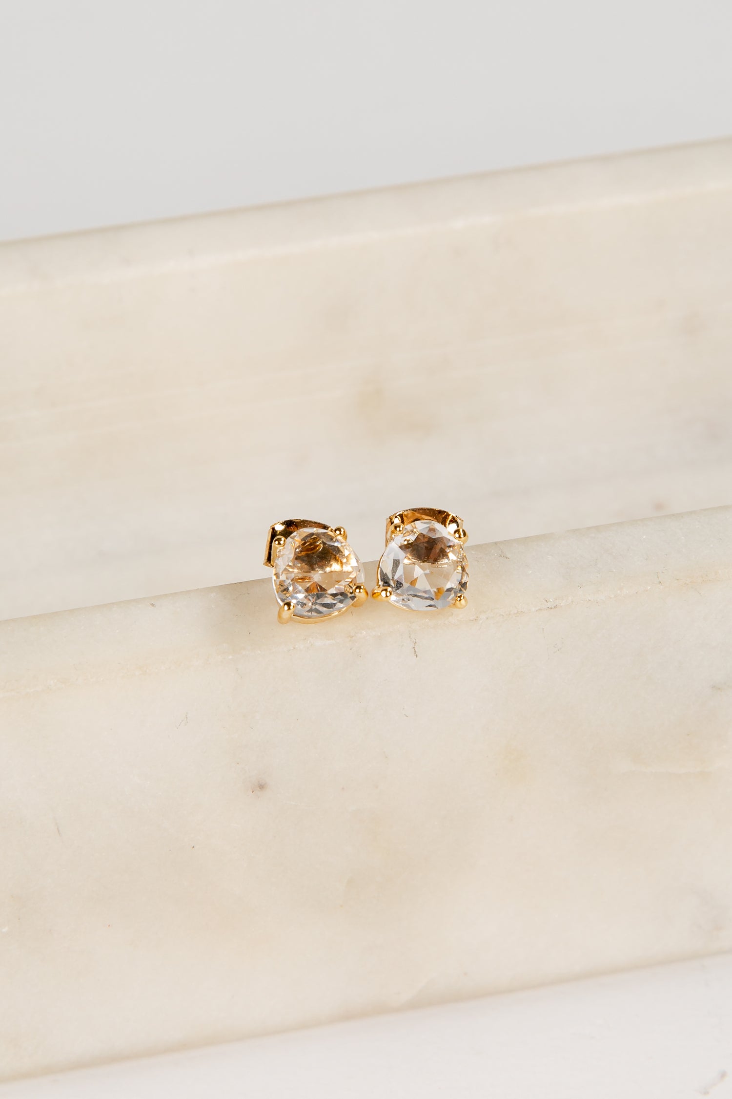 Gold stud earrings on a marble surface