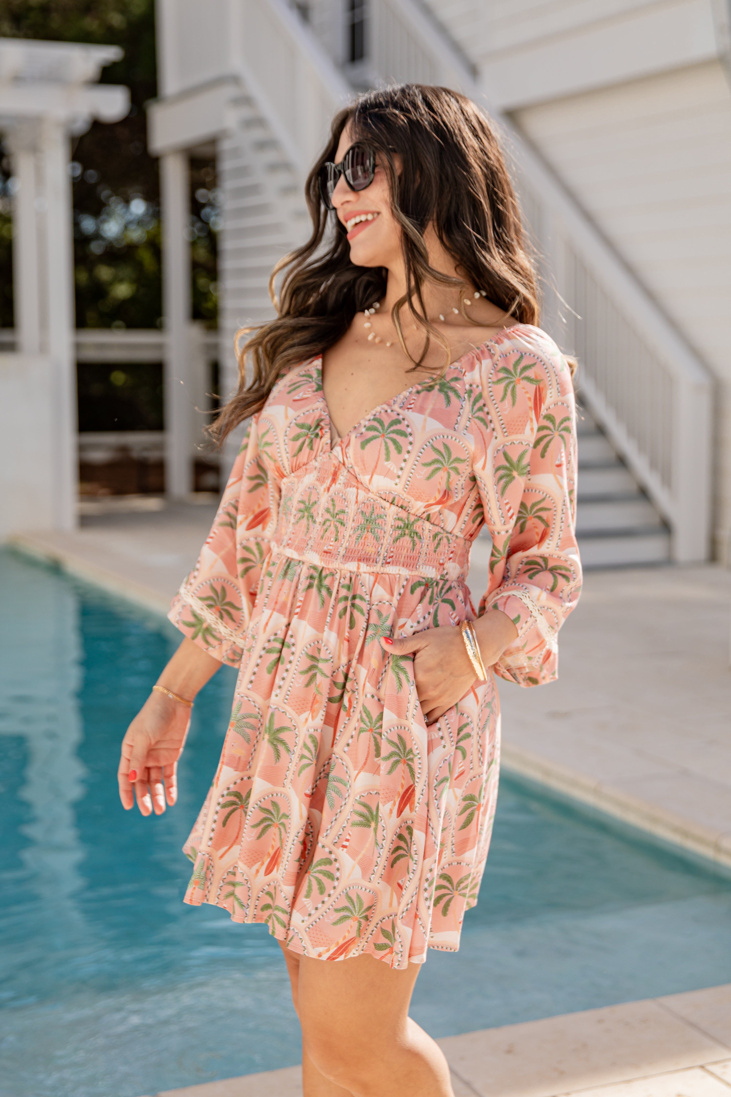 Woman in a pink floral dress standing by a pool
