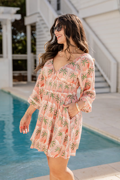 Woman in a pink floral dress standing by a pool