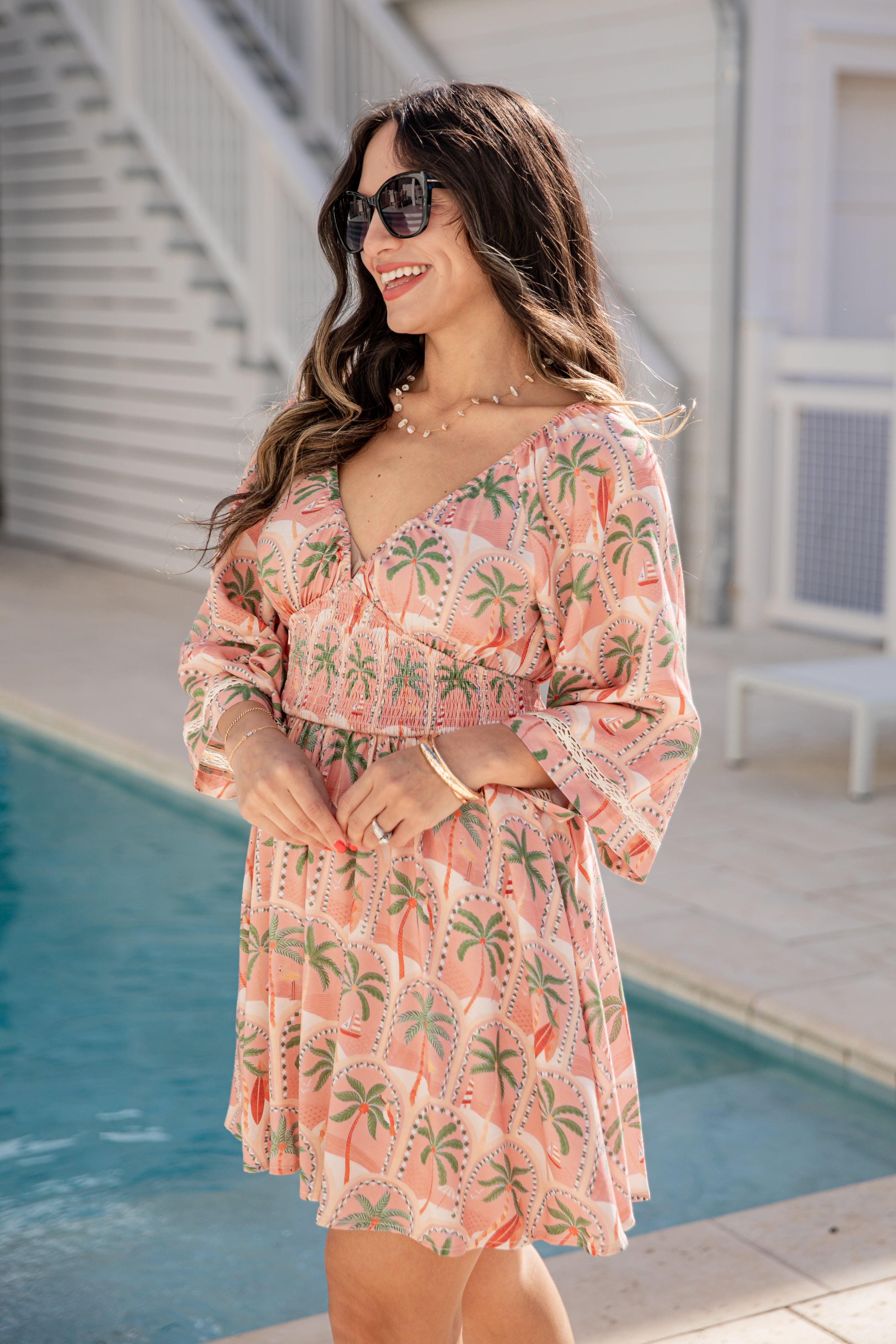 Woman in a tropical print dress standing by a pool
