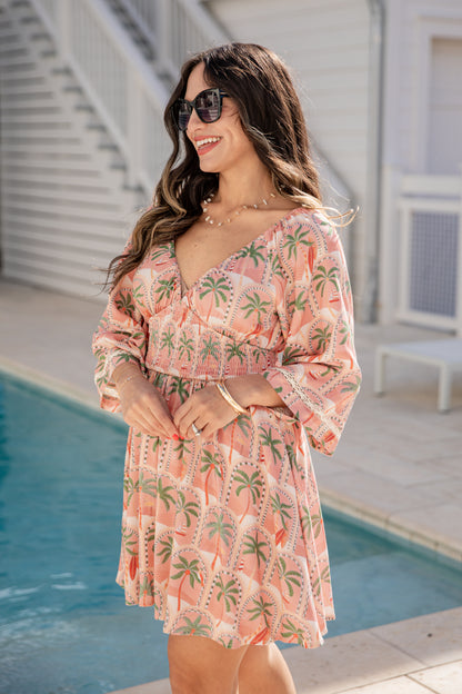 Woman in a tropical print dress standing by a pool
