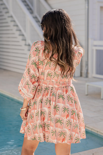 Woman in a floral dress standing by a poolside.