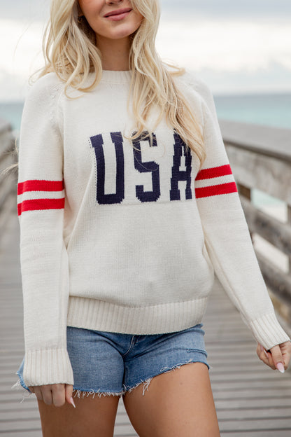 Person wearing a white sweater with &