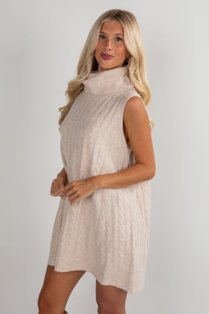 Woman wearing a beige sleeveless dress against a plain background