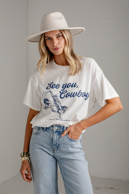 A woman wearing a white graphic t-shirt with a blue &