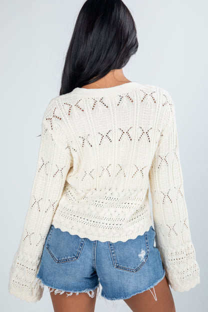 Person wearing a white lace top and denim shorts on a plain background