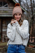Woman wearing a beige knit hat and white sweater outdoors