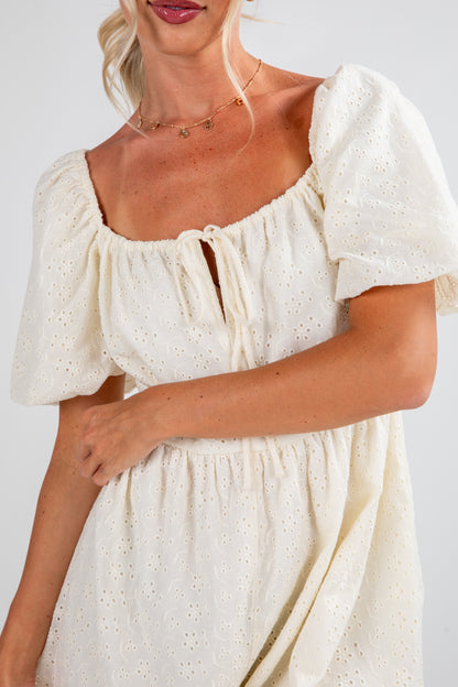 Woman wearing a white dress with puff sleeves against a plain background