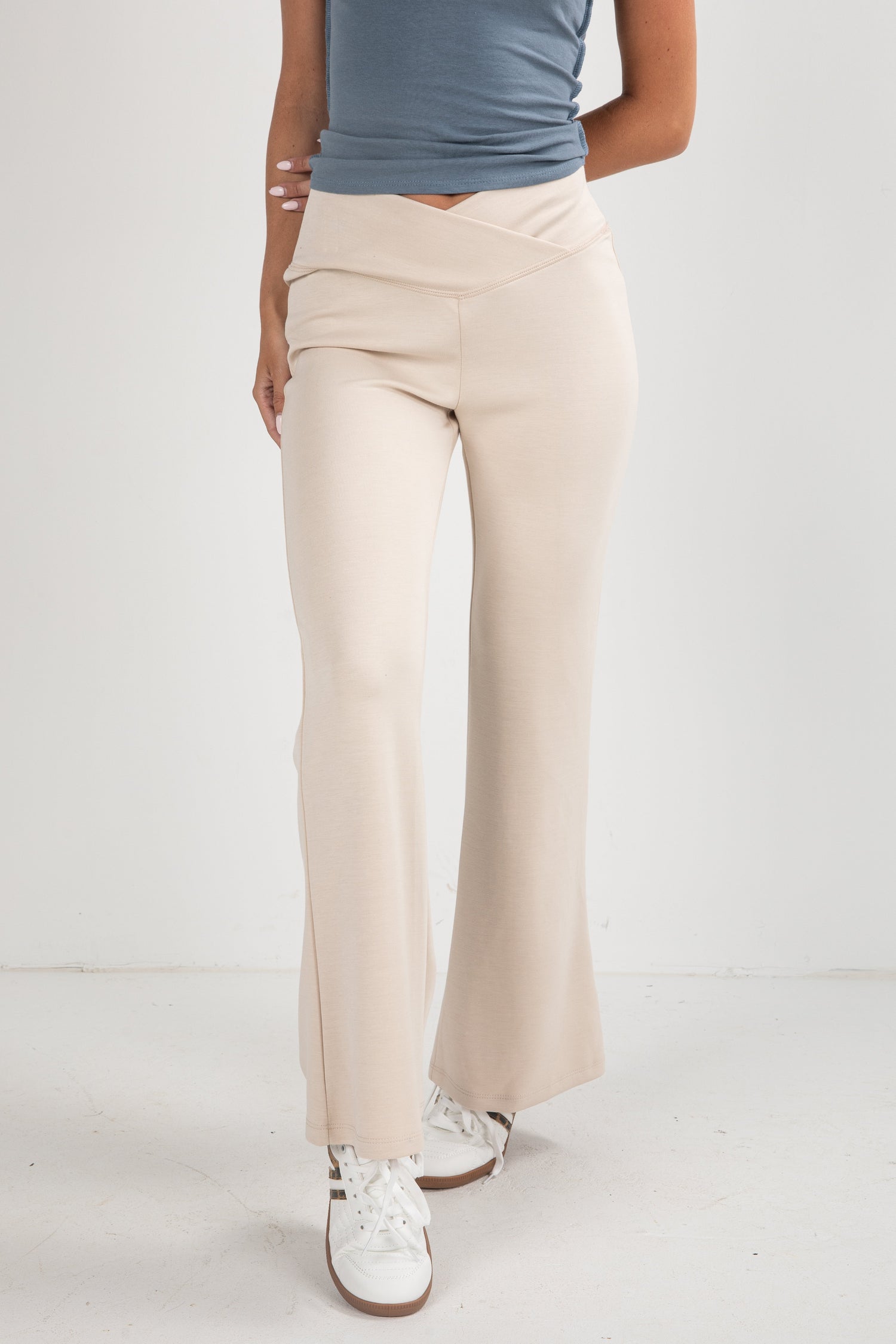Person wearing beige wide-leg pants and a blue top on a white background