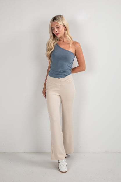 Woman wearing a blue top and beige pants against a white background