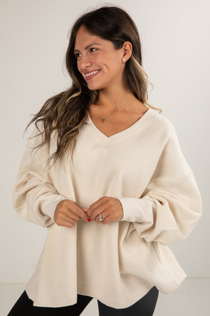 Woman wearing a beige sweater against a plain background