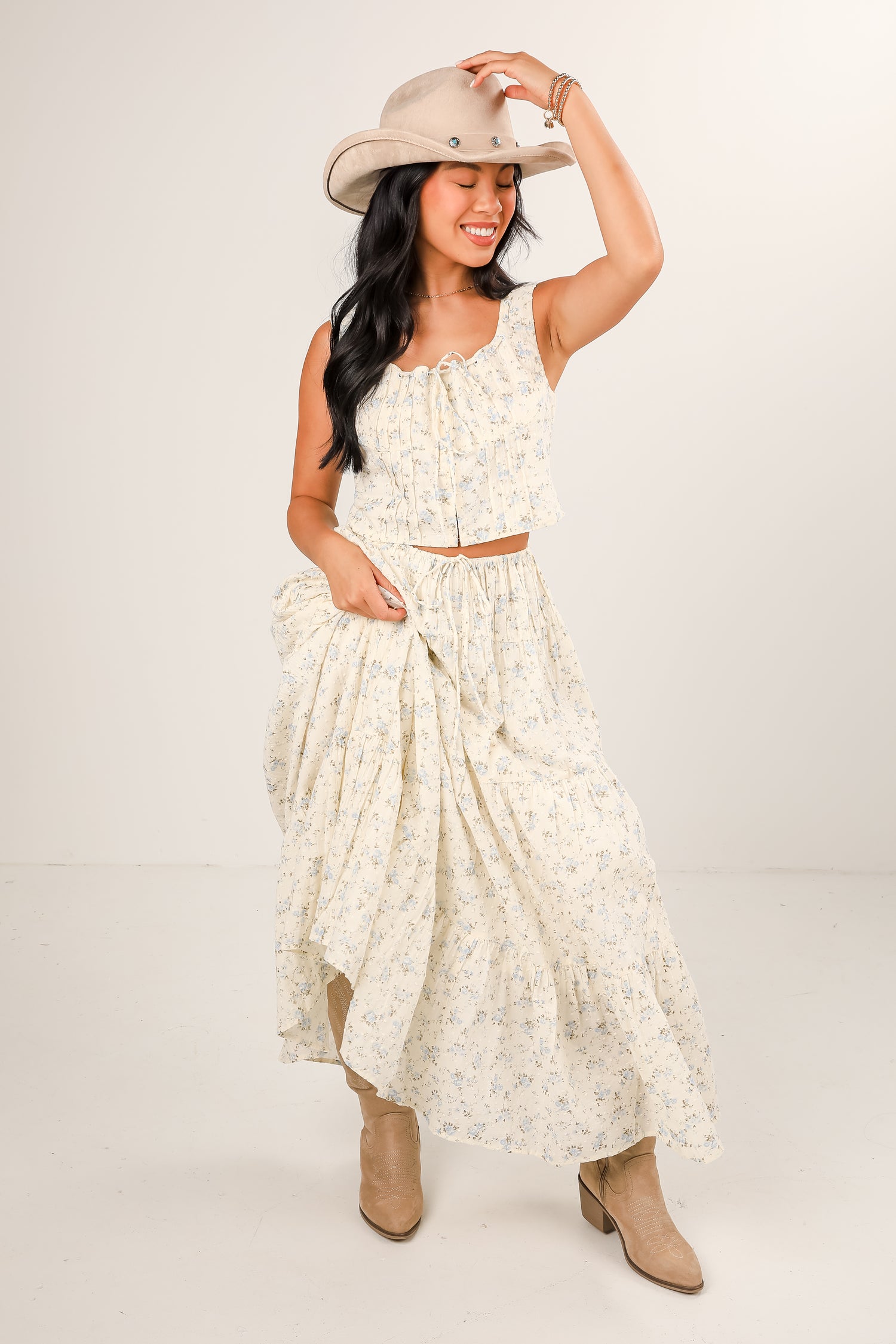 Woman wearing a white floral dress and beige hat on a plain background