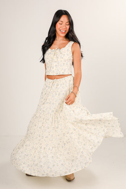 Woman wearing a white floral dress against a plain background