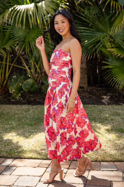 Woman in a floral dress standing outdoors with greenery in the background