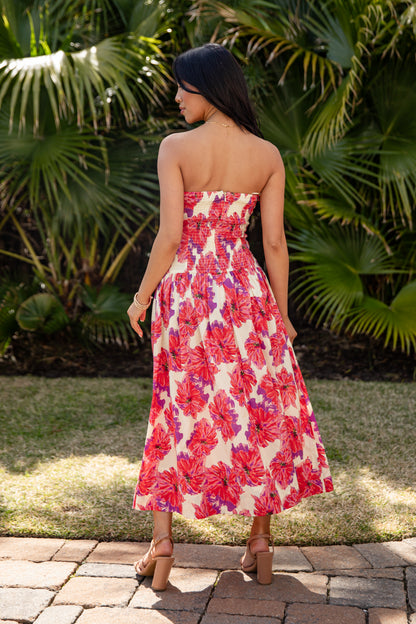 Woman in a strapless floral dress standing in front of palm trees
