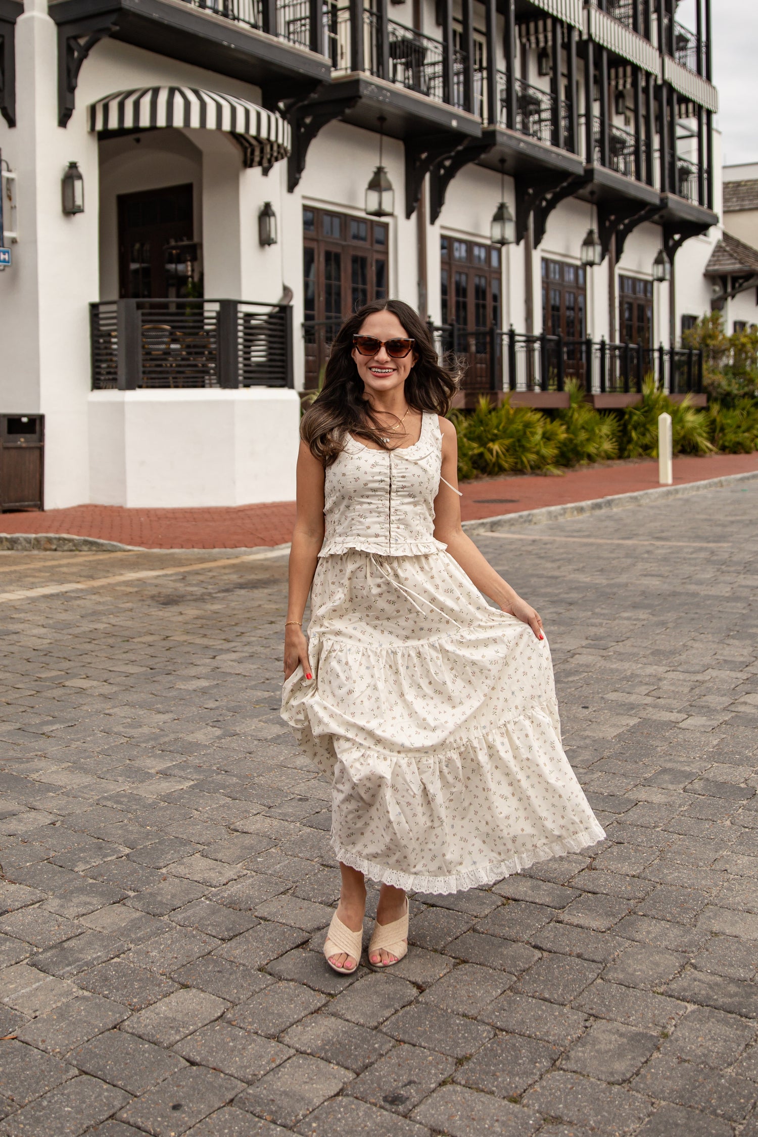 Woman in a white dress standing on a cobblestone street with a building in the background