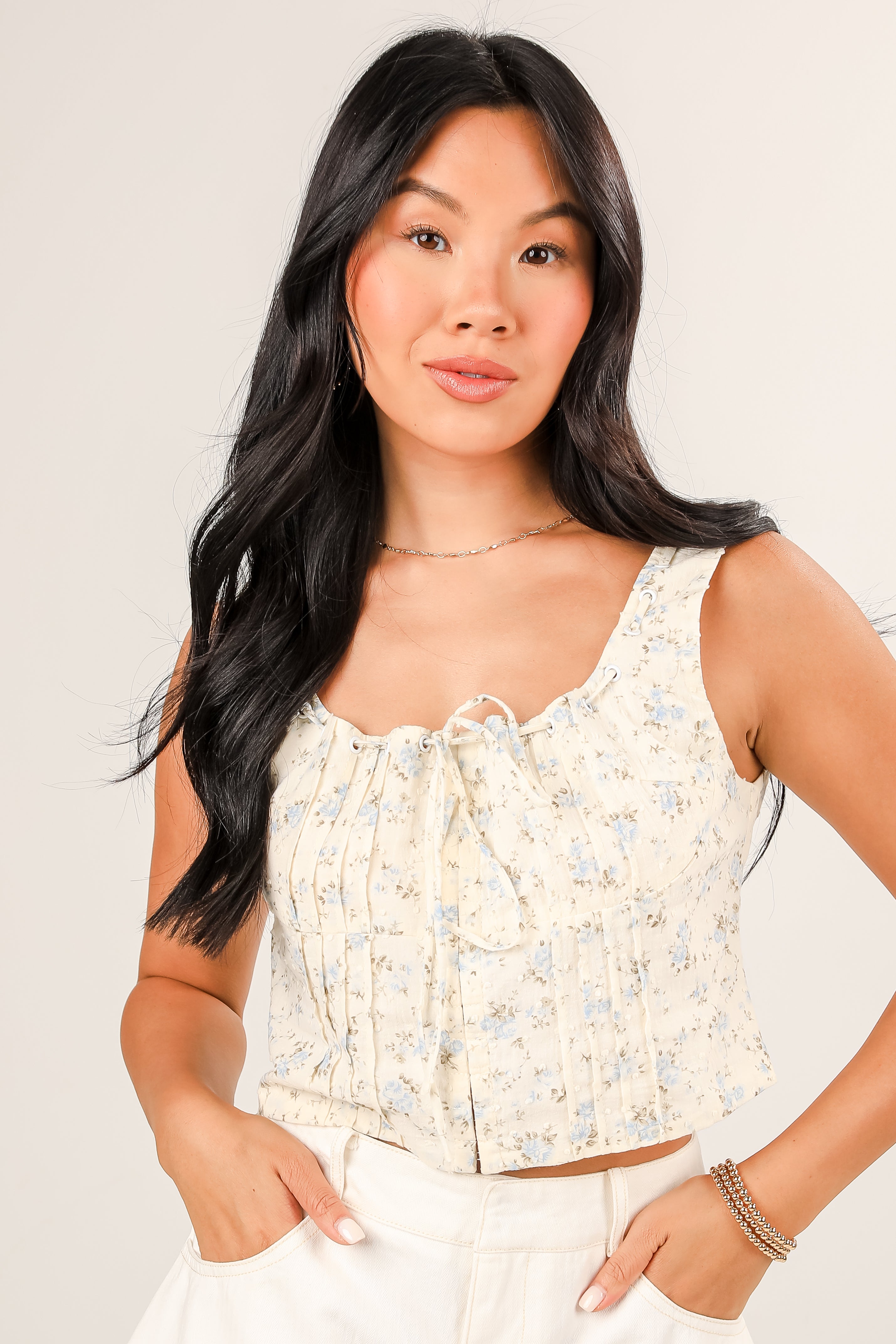 Woman wearing a floral sleeveless top against a plain background