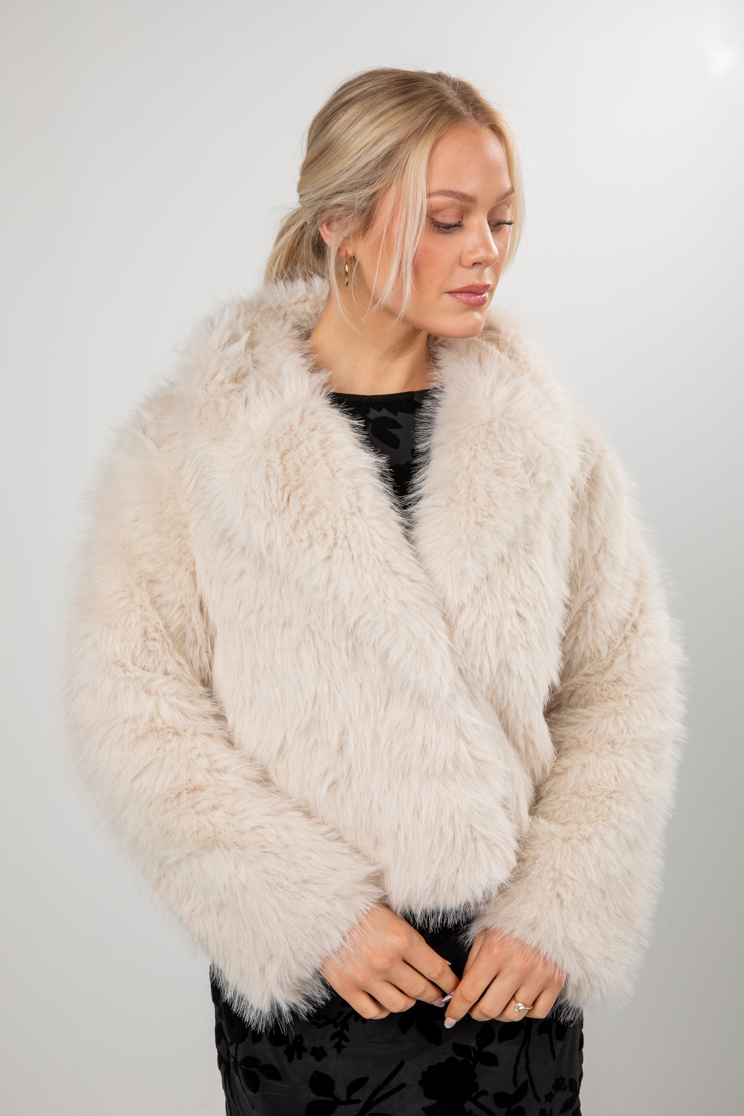 Woman wearing a fluffy beige coat against a plain background