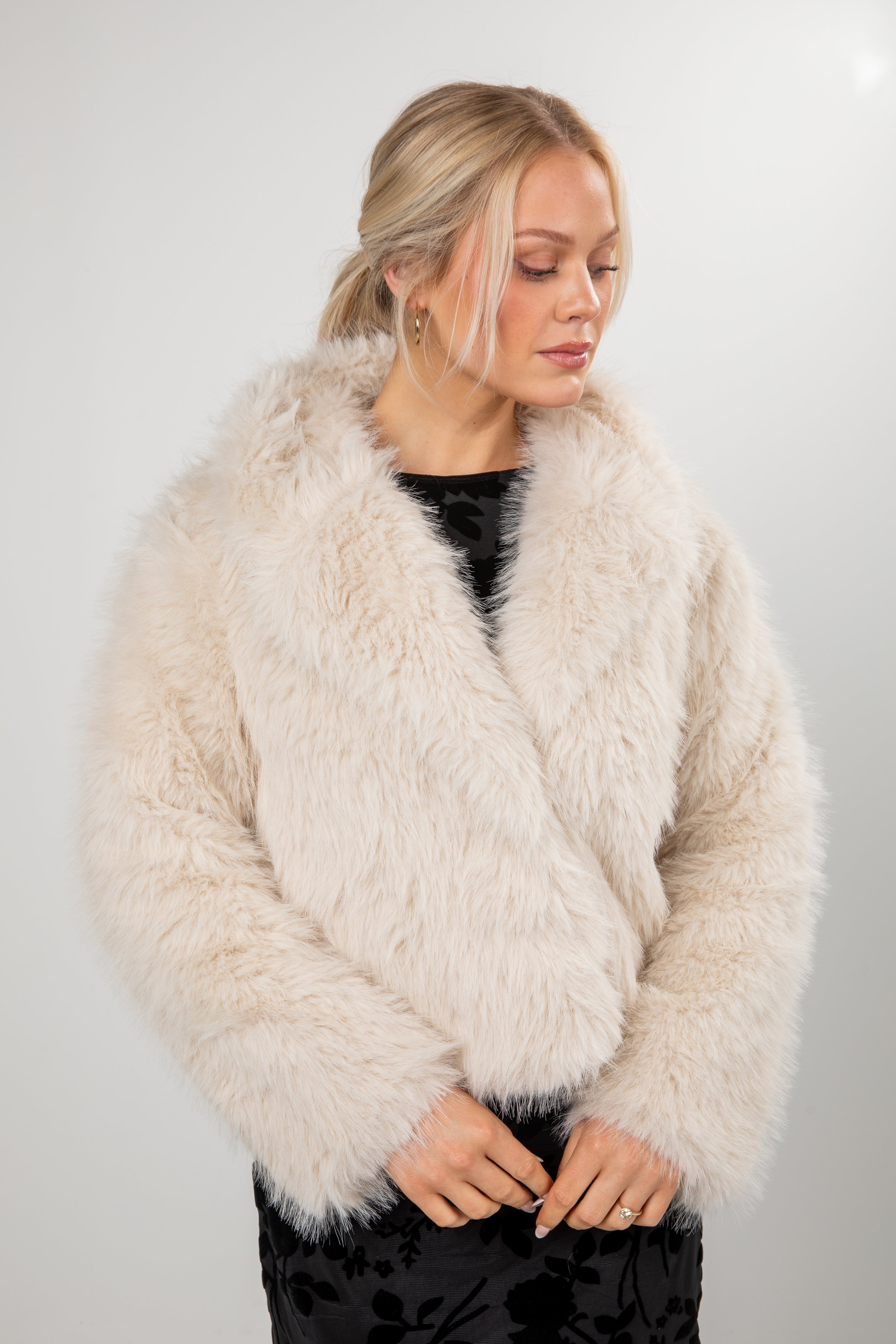 Woman wearing a fluffy beige coat against a plain background