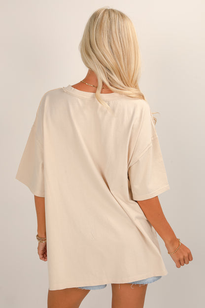 Woman wearing a beige oversized t-shirt on a plain background