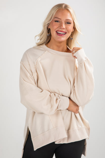 Woman wearing a beige sweater against a white background