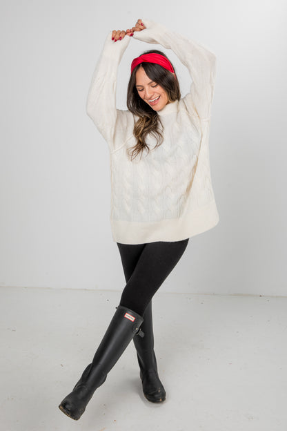 Woman wearing a white sweater, black leggings, and black rain boots on a white background