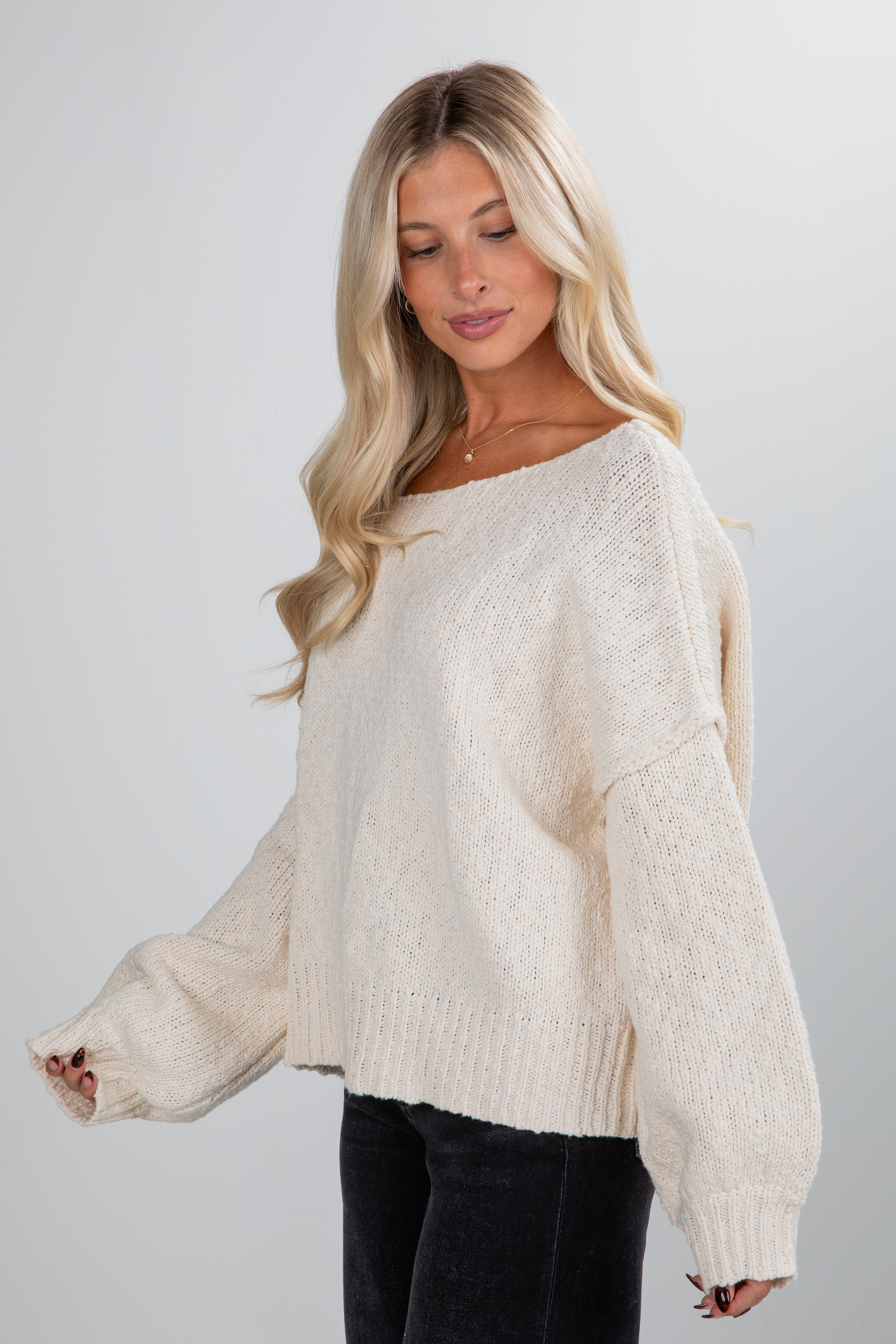 Woman wearing a cream sweater against a plain background