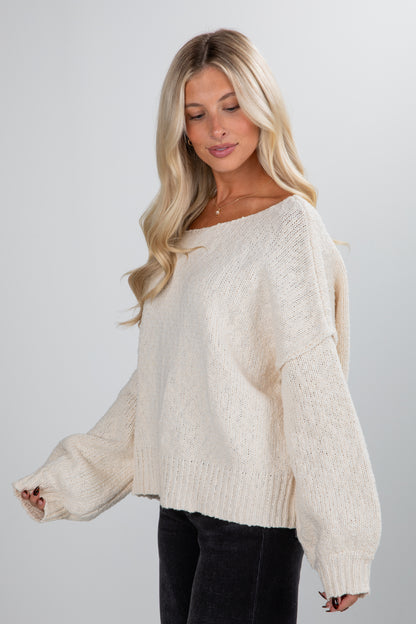 Woman wearing a cream sweater against a plain background
