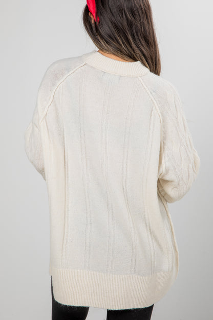 Beige sweater worn by a person against a plain background