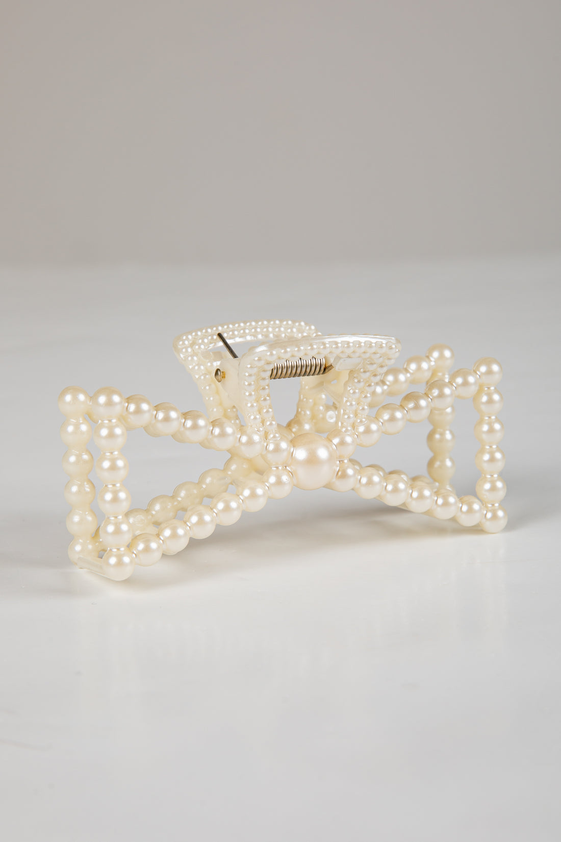 Pearl bow hair clip on a light gray background