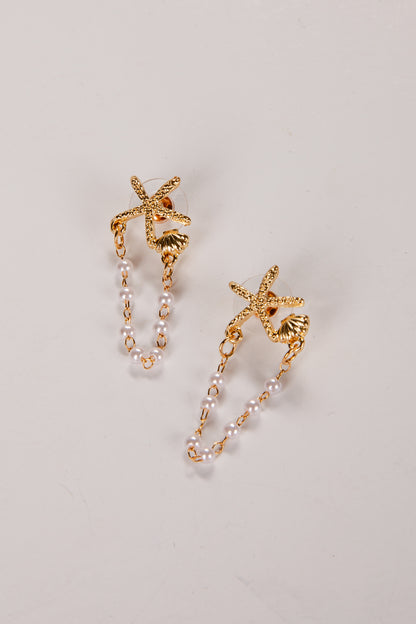 Gold starfish earrings with pearl-like beads on a light gray background