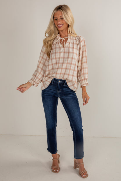 Woman wearing a plaid shirt and blue jeans on a plain background