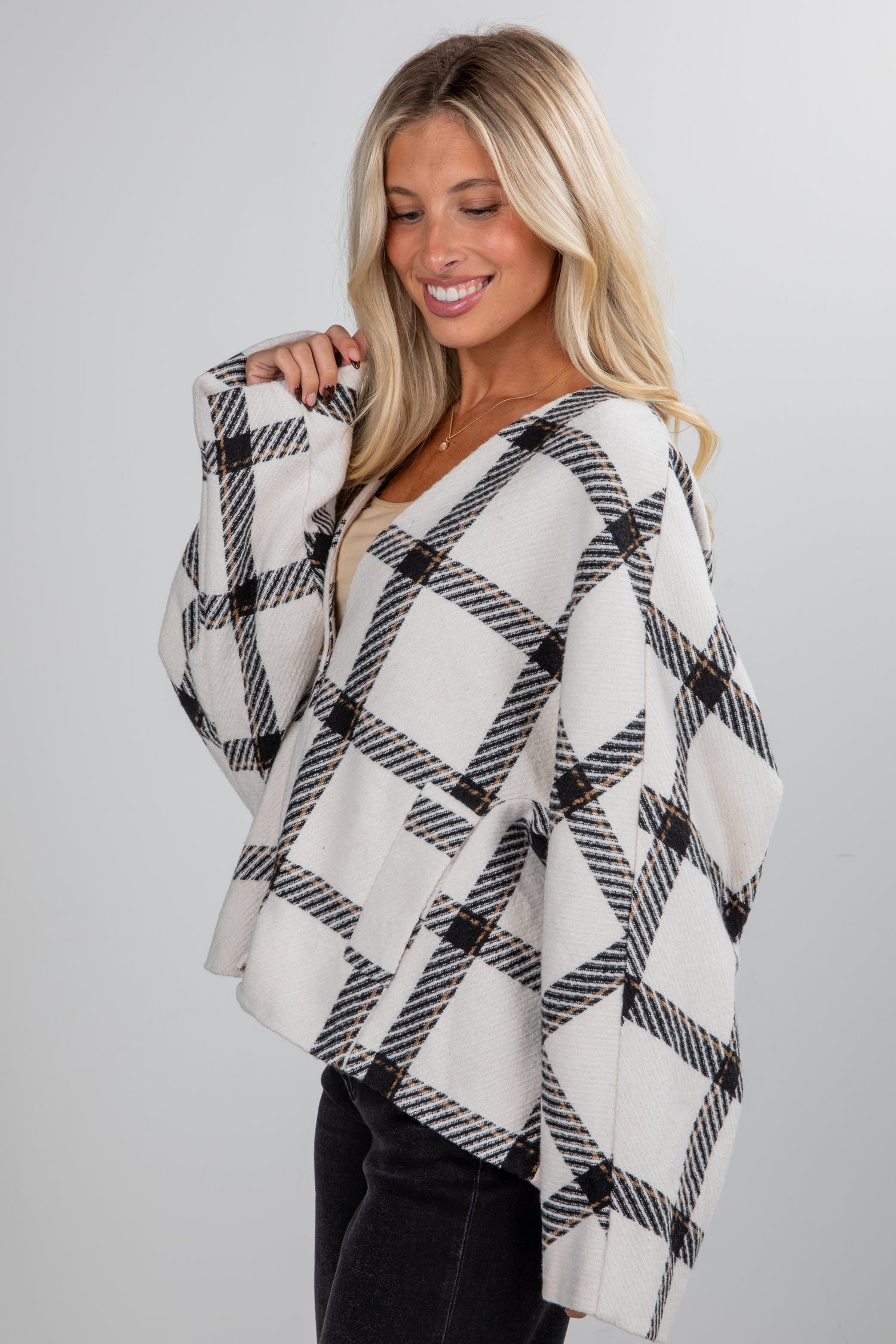 Woman wearing a black and white plaid poncho against a gray background
