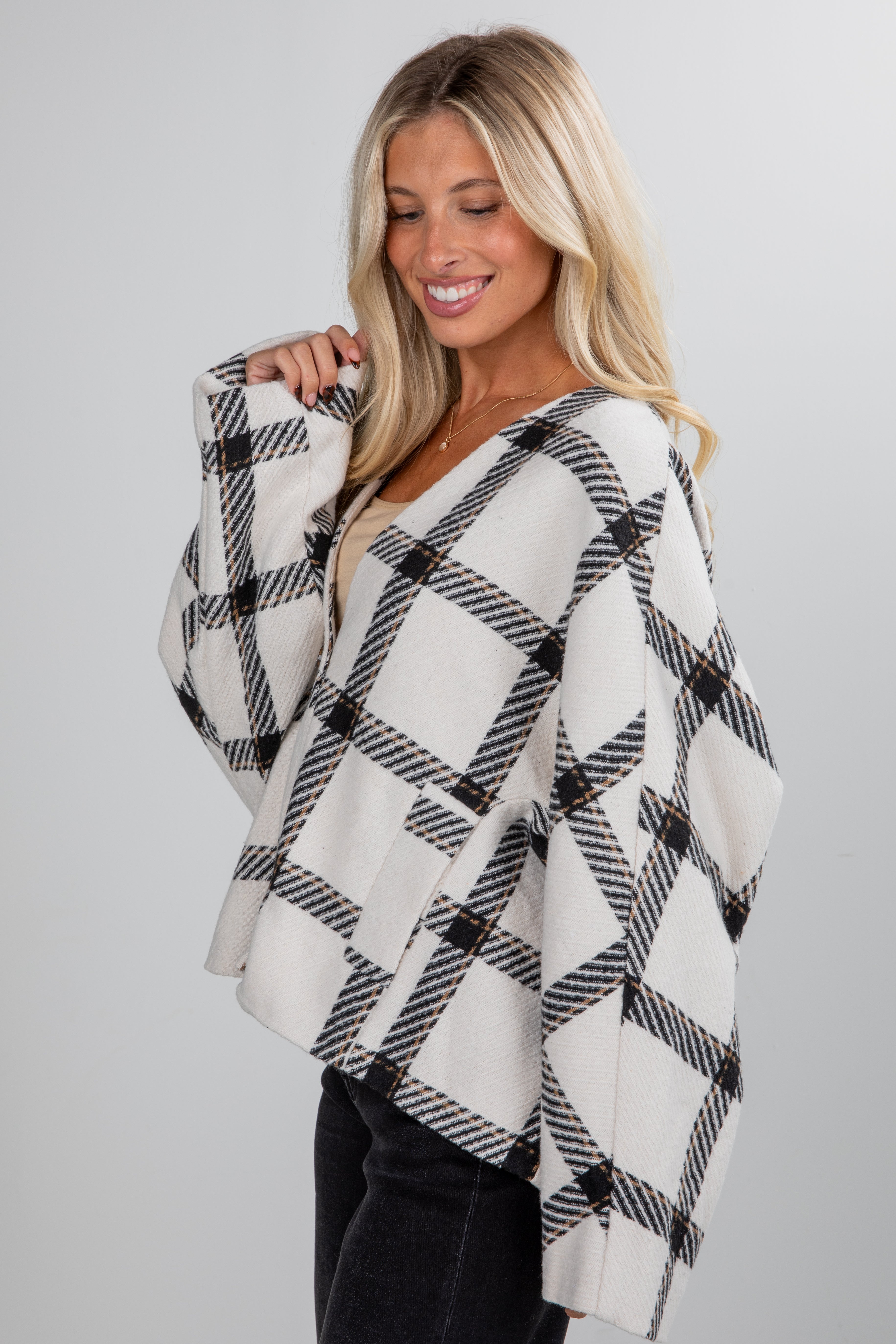 Woman wearing a black and white plaid poncho against a gray background