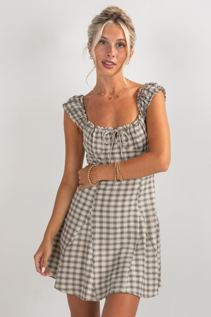 Woman wearing a checkered dress against a plain background