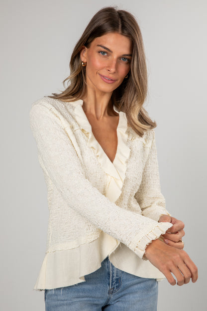 Woman wearing a white lace top and blue jeans on a gray background