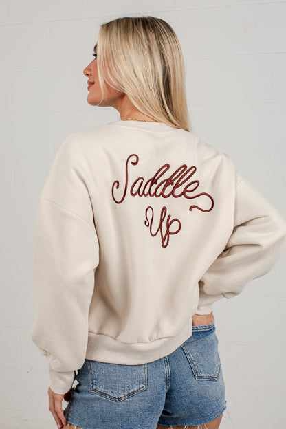 A woman shown from the back wearing a cream-colored crewneck sweatshirt with &