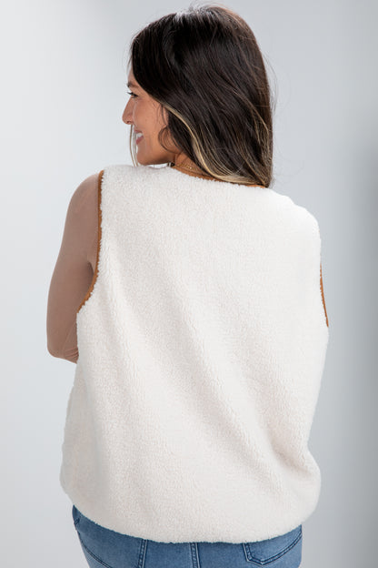 Woman wearing a white sleeveless sweater vest against a plain background